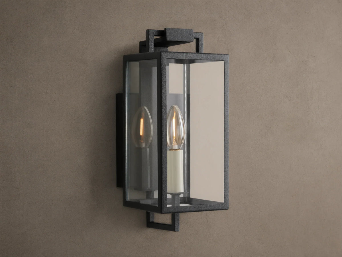 Hendricks Outdoor Sconce: black iron rectangular lantern, clear glass, two candle-style bulbs, mounted on a taupe wall.